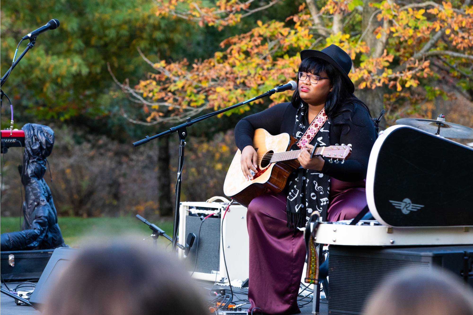 A student singing and playing guitar in the arboretum